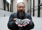 Ai Weiwei holding some of his sunflower seeds at Tate Modern