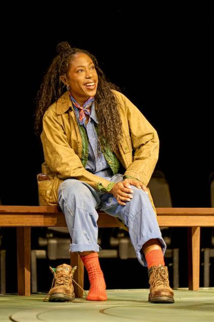 Nikki Amuka-Bird as Hannah, sitting on a bench with one shoe on, one off